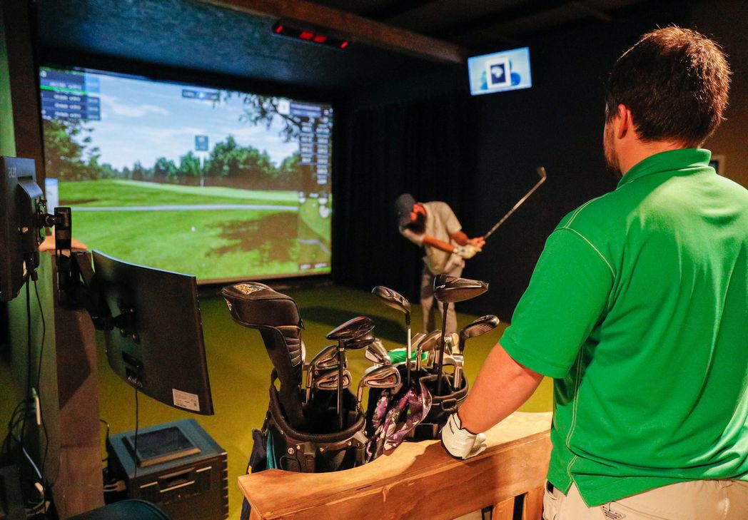 Golfer swinging in a simulator bay
