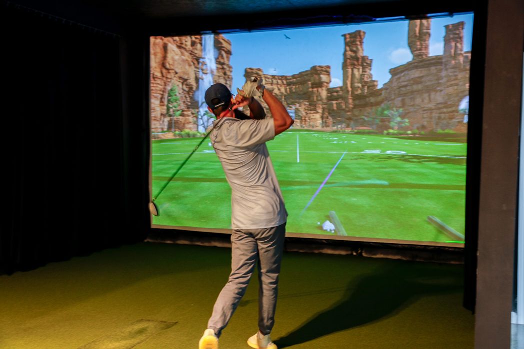 Golfer swinging at a canyon course on the simulator screen