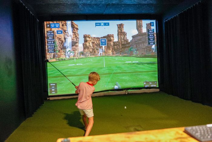 Child swinging a club in a simulator bay